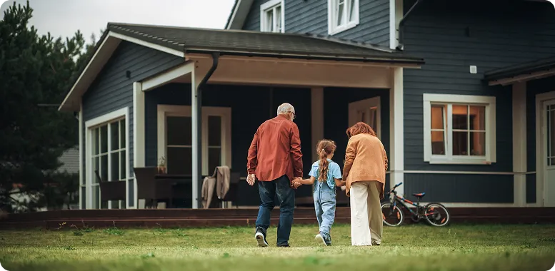 Older couple with young child walking towards a home