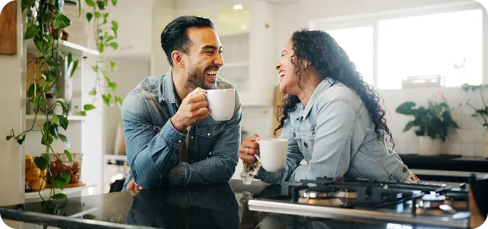 Two people laughing and drinking coffee in the kitchen - Home Equity Loan