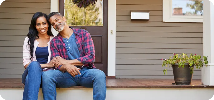 Couple sitting on porch steps in front of their home