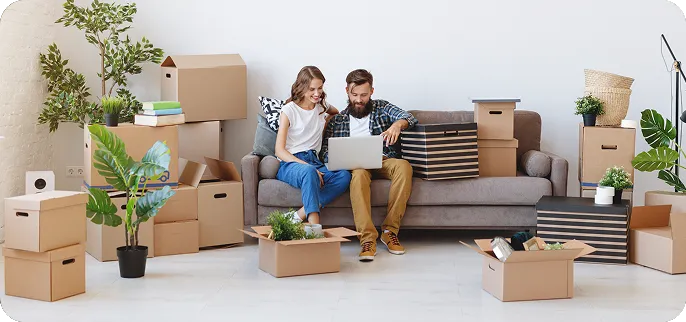 Couple sitting in front of laptop surrounded by moving boxes - purchase loan