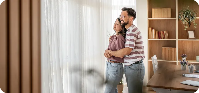 Hugging couple in front of window