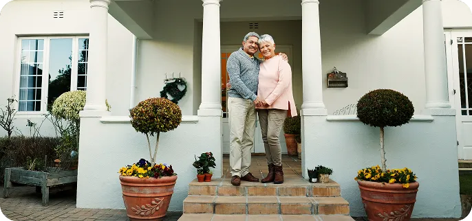 Senior couple standing in front of home